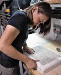 Artist pressing clay into a plaster tile mold