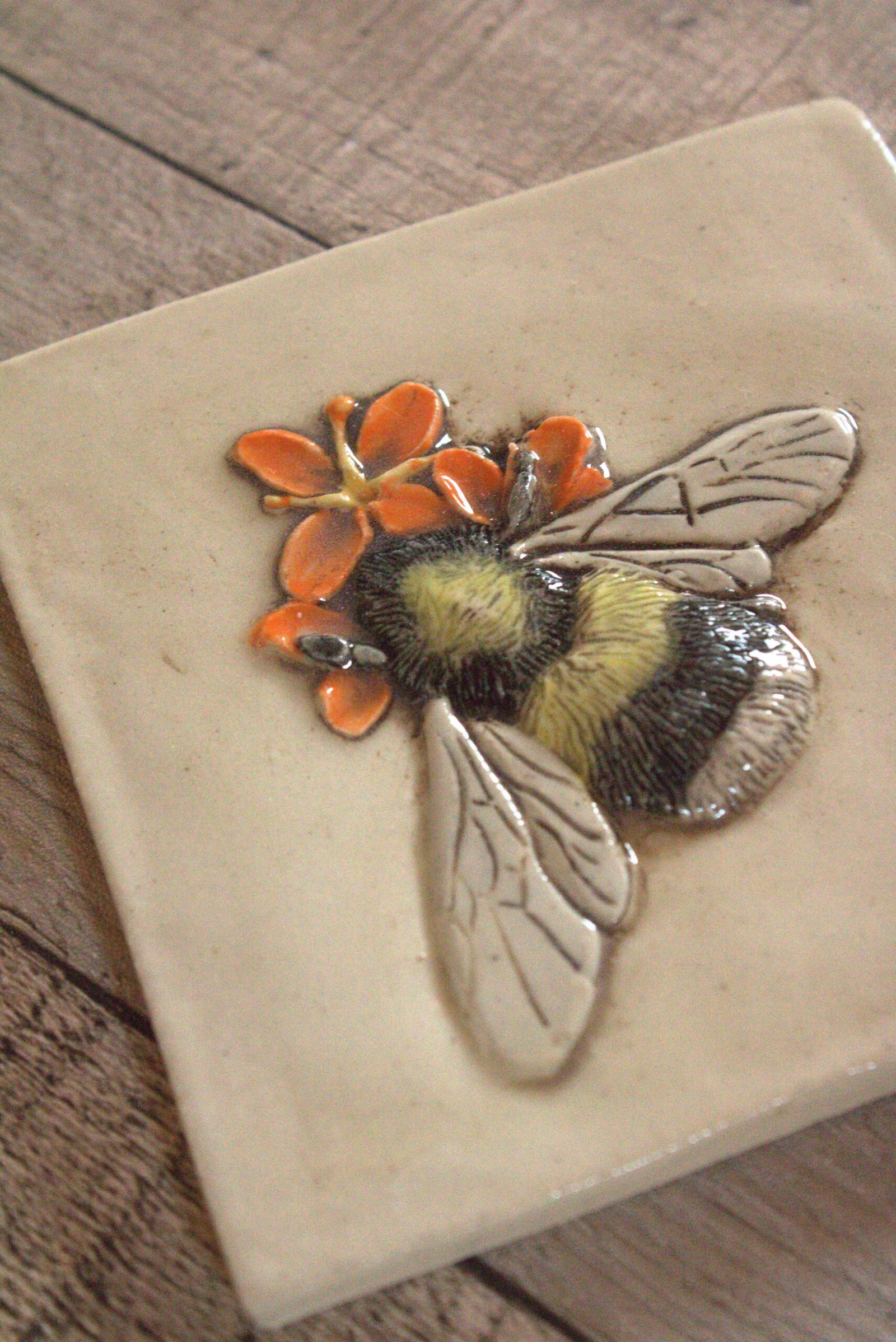 photo showing hand carved detail of a black, yellow and white bumble bee ceramic tile