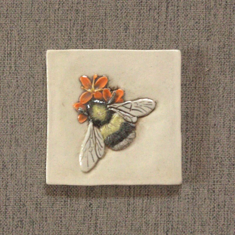 Black, yellow, and white bumble bee sitting on an orange flower ceramic tile
