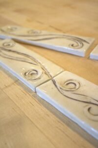 Handcrafted ceramic border tile with a flowing meadow breeze design inspired by the gentle movement of a Wyoming Mountain Breeze