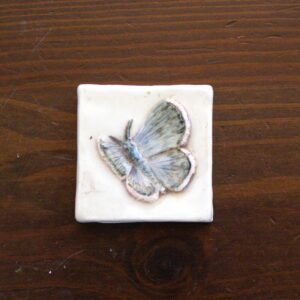 Handmade 2-inch Silvery Blue Butterfly ceramic tile from the Meadow Bloom Collection featuring a hand-carved butterfly design with soft blue tones.